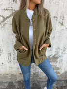 Frau in olivgrüner Strickjacke, lässig über weißem T-Shirt und blauen Jeans. Modetrend, Herbstmode, Damenbekleidung, Streetstyle.