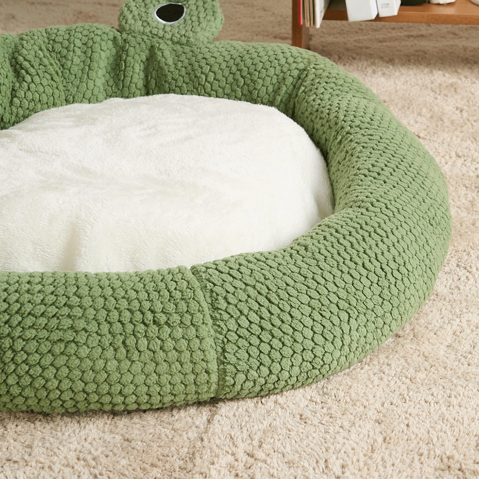 Grünes Haustierbett aus Plüsch, rund, gemütlich, ideal für Hunde und Katzen, auf Teppichboden.