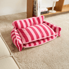 Rosa-gestreiftes Katzen-Sofa aus Lammwolle auf Teppich, gemütliches Haustierbett.