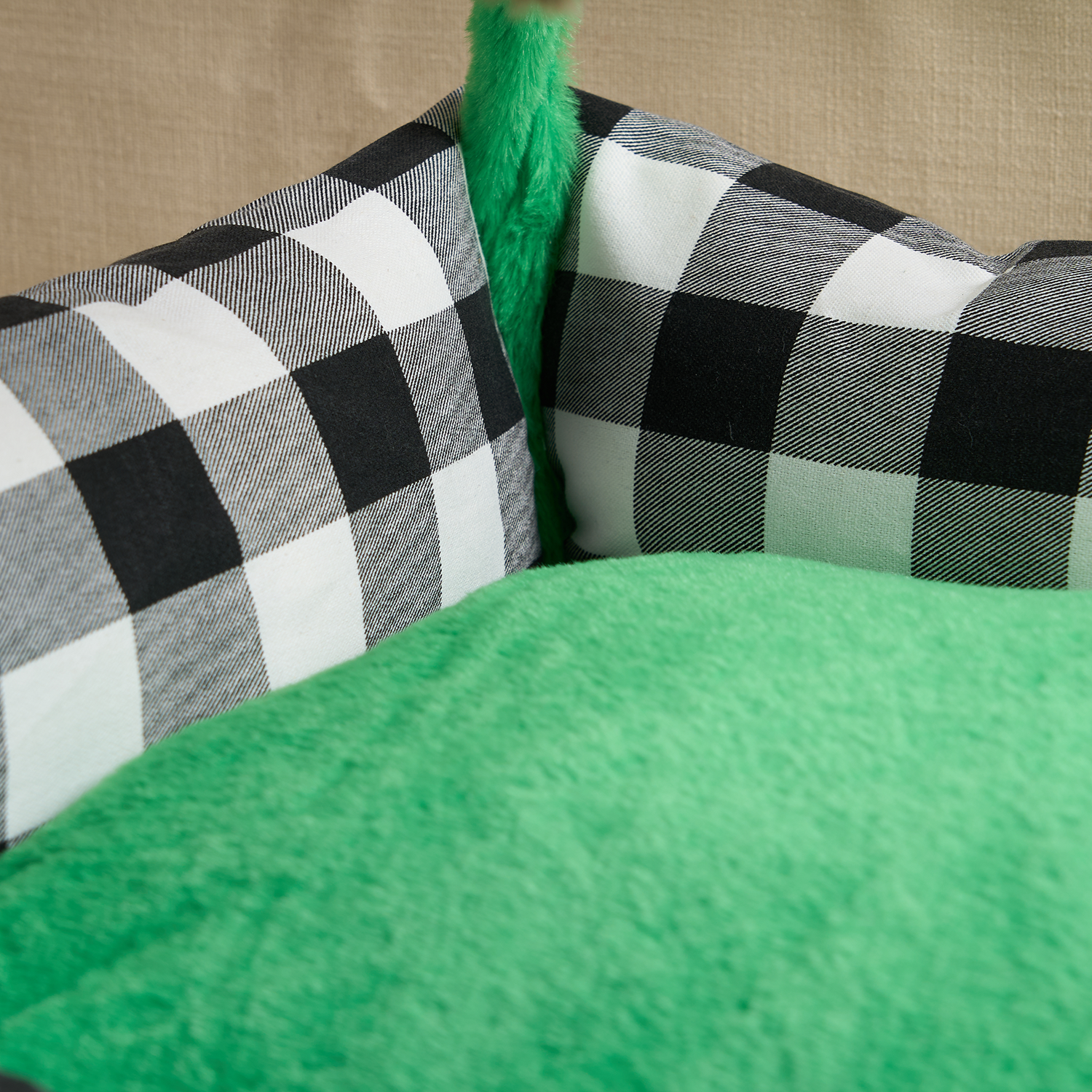 Schwarz-weiß kariertes Katzenbett mit grünem Plüsch, gemütlich und interaktiv.