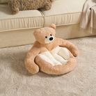 Kuscheliges Bären-Katzenbett aus Plüsch, beige, auf Teppich vor Sofa, Haustierbett für Katzen.