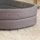 Graues Hundebett aus Stoff auf Teppich, rund und gepolstert, ideal für Haustiere.