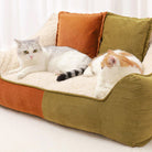Katzen und Hund auf gemütlichem, zweifarbigem Haustier-Sofa mit Kissen, orange und grün.