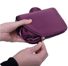 Hände halten lila faltbare Reisetasche mit Reißverschluss, kompakt und tragbar.