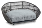 Graues Rattan-Hundebett mit hellblauem Kissen, stilvolles Haustiermöbel, robust und bequem.