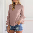 Damenbluse mit Rüschenärmeln in Rosa, kombiniert mit zerrissenen Jeansshorts. Modetrend, lässiger Look, stilvolle Freizeitkleidung.