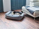 Hundebett grau, gesteppter Stoff, Hund liegt bequem, modernes Wohnzimmer, Holzboden.