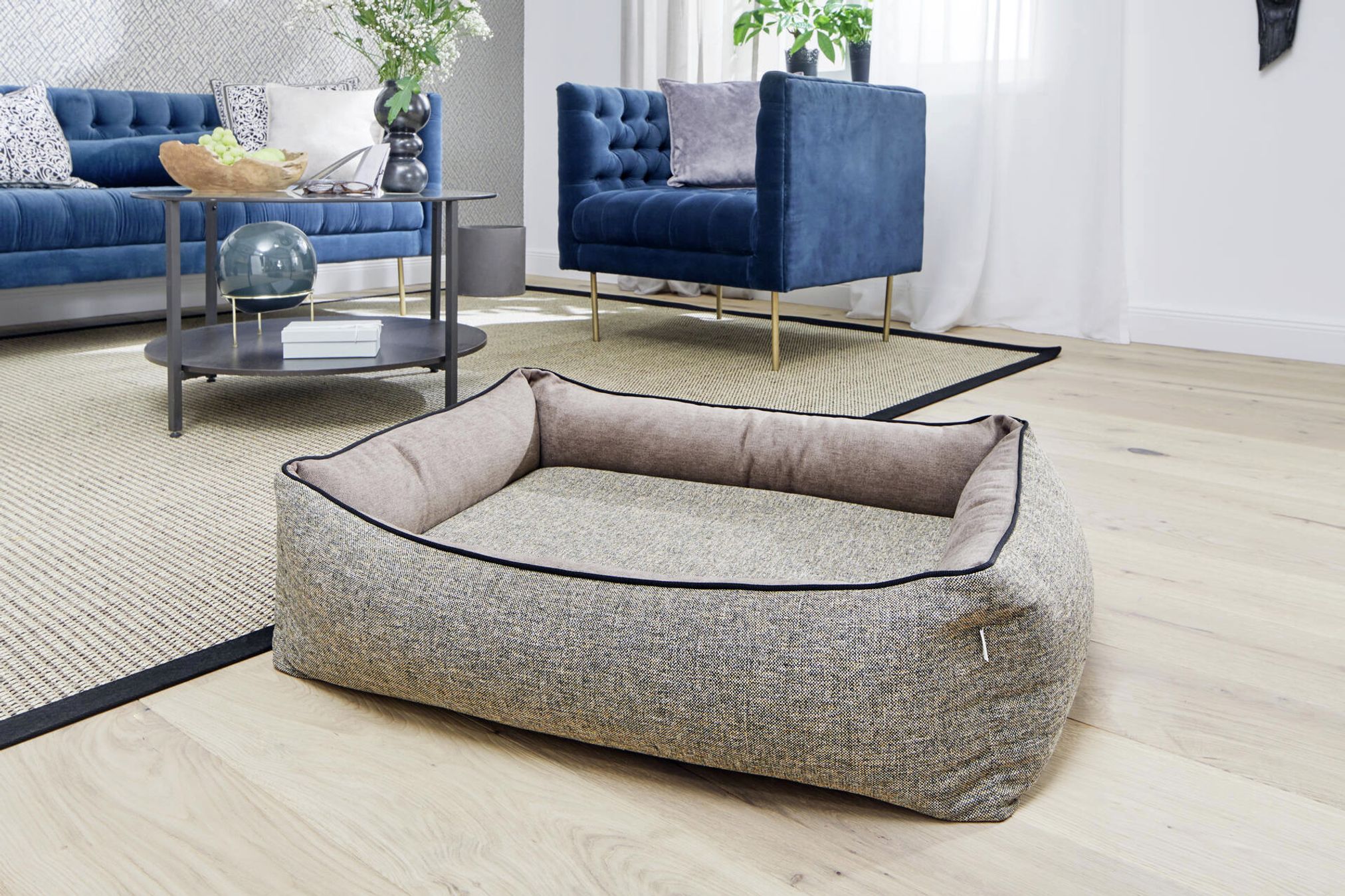 Rechteckiges, graues Hundebett aus Stoff im modernen Wohnzimmer auf Holzboden.