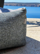 Graues Outdoor-Sitzkissen am Wasser, robustes Material, ideal für Terrasse oder Garten.