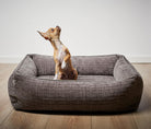 Braunes Hundebett aus Stoff mit kleinem Hund, rechteckig, gemütlich, für kleine Hunde geeignet.