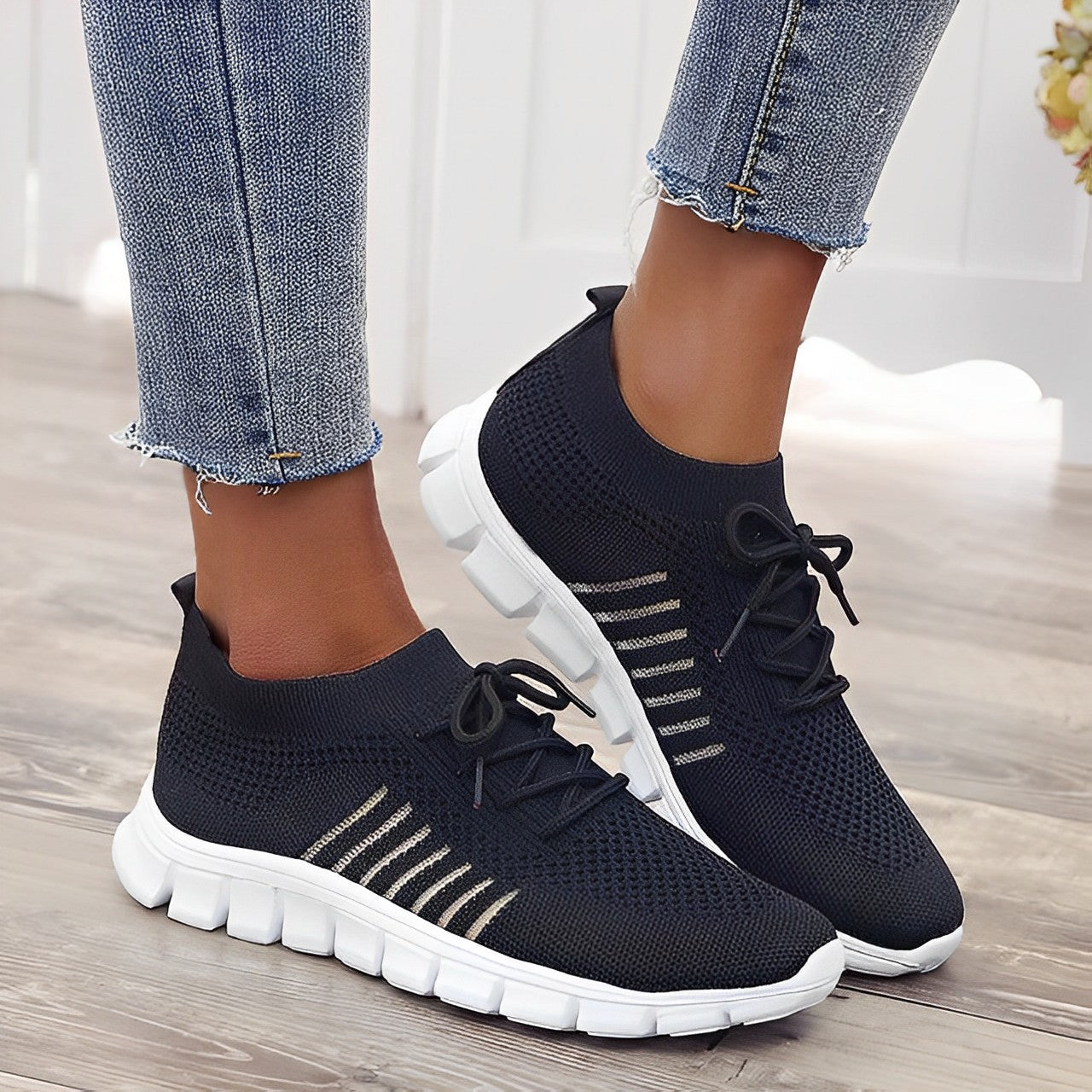 Damen Sneaker in Schwarz mit weißer Sohle, atmungsaktivem Mesh-Obermaterial und Schnürung, ideal für Sport und Freizeit.