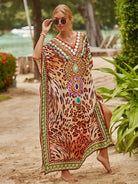Frau im eleganten Kaftan mit Leopardenmuster und bunten Verzierungen am Strand. Sommermode, Boho-Chic, Strandkleidung, Damenmode.