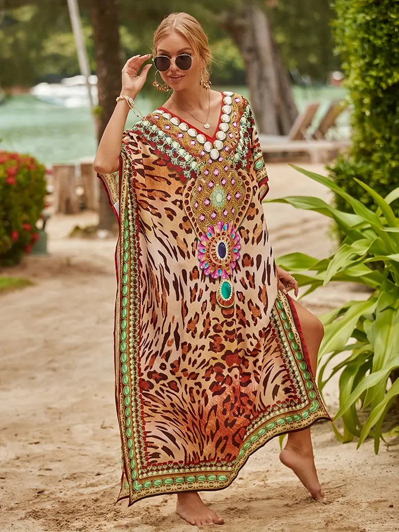 Frau im eleganten Kaftan mit Leopardenmuster und bunten Verzierungen am Strand. Sommermode, Boho-Chic, Strandkleidung, Damenmode.