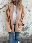 Damenmode: Beige Strickjacke, lässig über weißem T-Shirt und blauen Jeans getragen. Perfekt für Herbst-Outfits und gemütliche Streetwear.