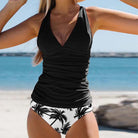 Damen-Badeanzug mit schwarzem Oberteil und Palmenmuster am Strand. Sommermode, Strandbekleidung, stilvoller Badeanzug, Urlaub.