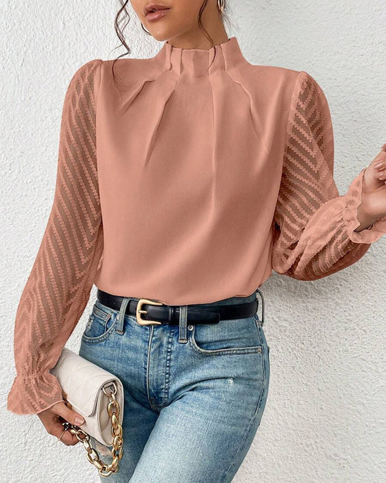 Damenbluse mit Stehkragen und transparenten Ärmeln, kombiniert mit blauer Jeans. Elegante Mode, ideal für stilvolle Freizeit- und Büro-Outfits.