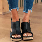 Schwarze Plateau-Sandalen aus Leder mit offenem Zeh, kombiniert mit zerrissenen Jeans. Modische Damen-Schuhe für Sommer und Freizeit.