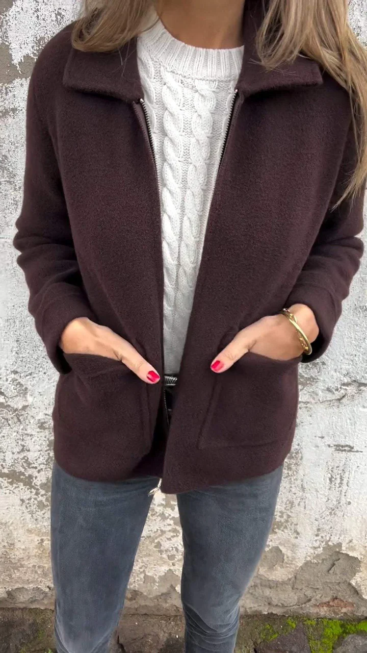 Damenmode: Eleganter brauner Wollmantel über weißem Strickpullover, kombiniert mit grauen Jeans. Perfekt für Herbst und Winter.