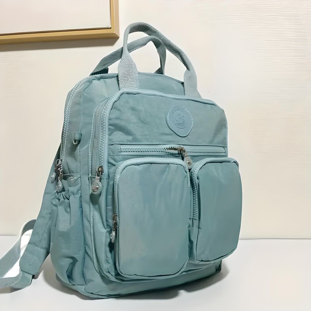 Hellblauer Rucksack mit mehreren Taschen, Reißverschlüssen, ideal für Schule oder Reisen.