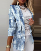 Damenblazer in Denim-Optik, kombiniert mit weißer Spitzenbluse und goldenen Accessoires. Modetrend, eleganter Look, Freizeitkleidung.