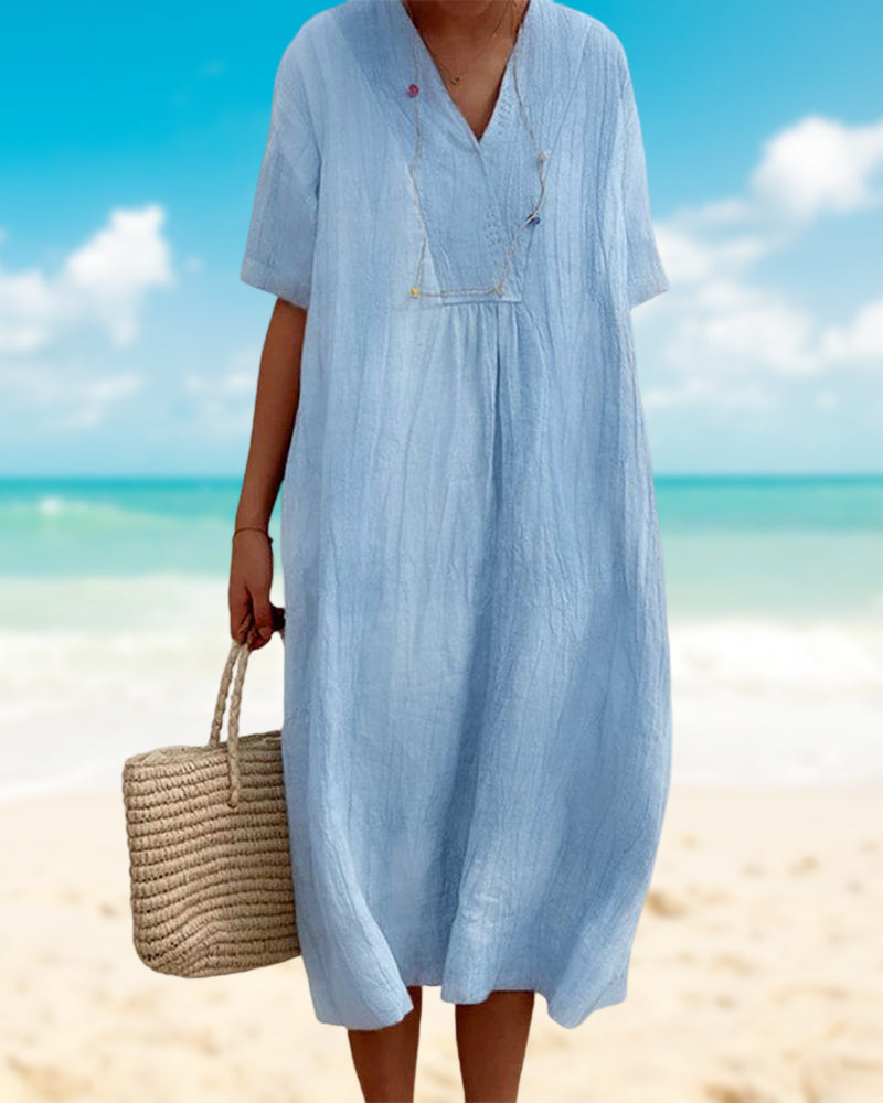 Frau in hellblauem Leinenkleid am Strand mit Strohtasche, Sommermode, Strandkleidung.