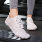 Weiße Barfußschuhe auf Laufband, ideal für Fitness und Laufen. Atmungsaktiv, leicht, ergonomisch. Perfekt für natürliche Fußbewegung.
