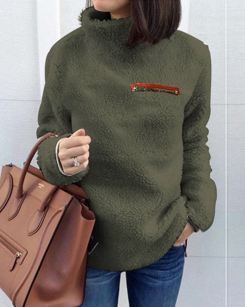 Damen Teddy-Fleece-Pullover in Olivgrün mit hohem Kragen und Reißverschluss-Detail, kombiniert mit brauner Lederhandtasche. Perfekt für Herbstmode.