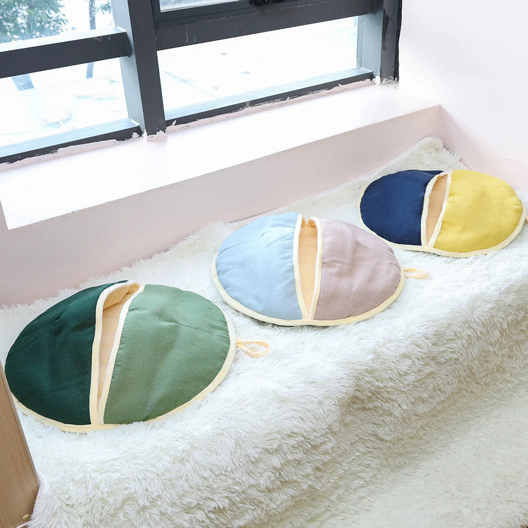 Runde Sitzkissen in Grün, Blau und Gelb auf weißem Fellteppich. Perfekt für modernes Wohndesign, gemütliche Dekoration und Komfort.