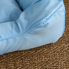 Wasserdichtes Kühl-Haustierbett, mittelgroß, hellblau, auf geflochtenem Teppich.