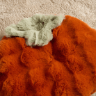 Orangefarbene Kunstfell-Schlafmatte auf beigem Teppich, luxuriös und weich, für gemütlichen Schlaf.