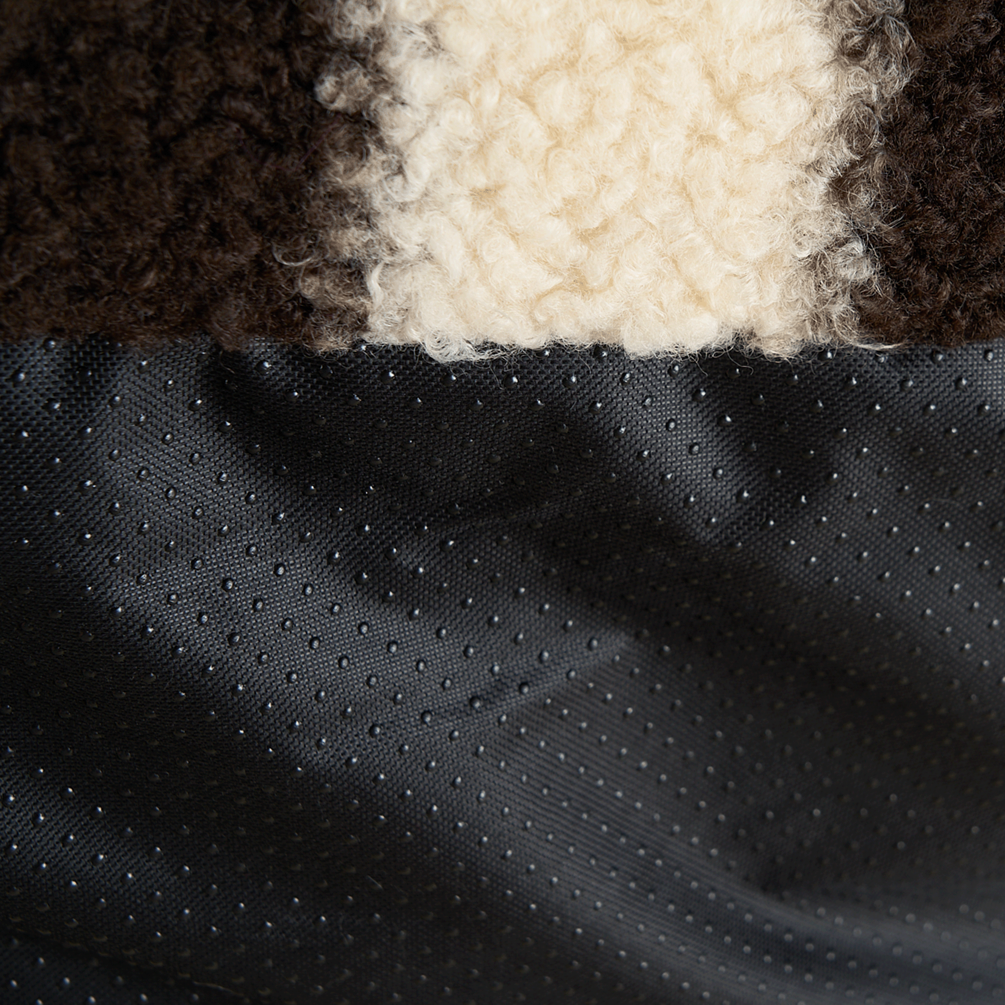 Nahaufnahme von gestreiftem Plüschstoff und gepunktetem schwarzen Material, Texturdetails.