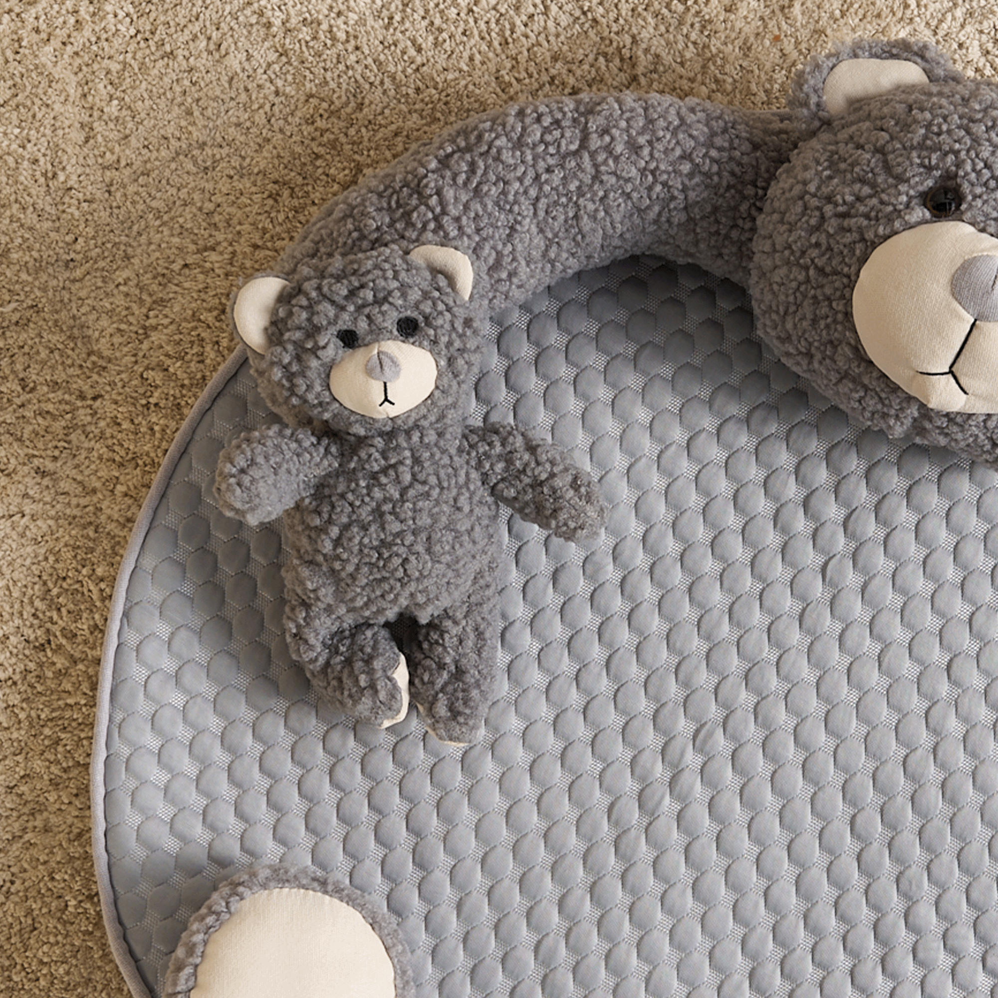 Graue Bären-Spielmatte aus Plüsch auf Teppich, ideal für Babys und Kleinkinder.