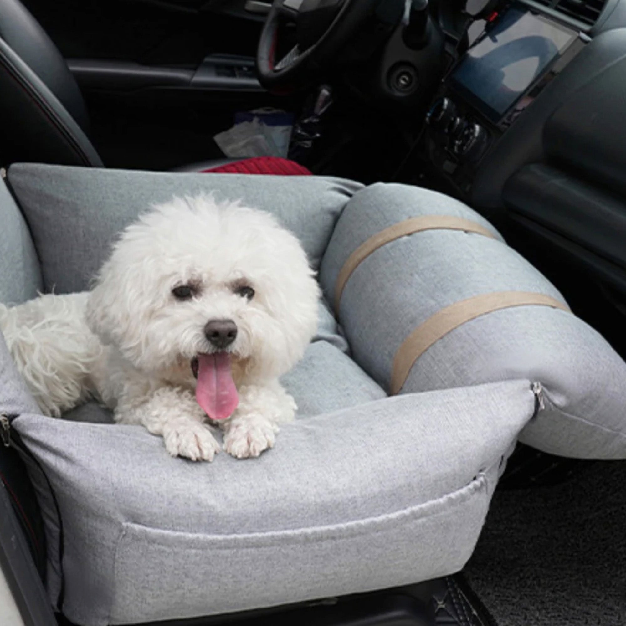 Weißer Hund in grauem orthopädischen Autositz für Haustiere, sicherer Hundesitz im Auto.