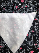 Schwarzer Stoff mit weißem und rosa Blumenmuster, detailreich und elegant. Ideal für Mode, Nähen und kreative Projekte. Hochwertige Textilien.