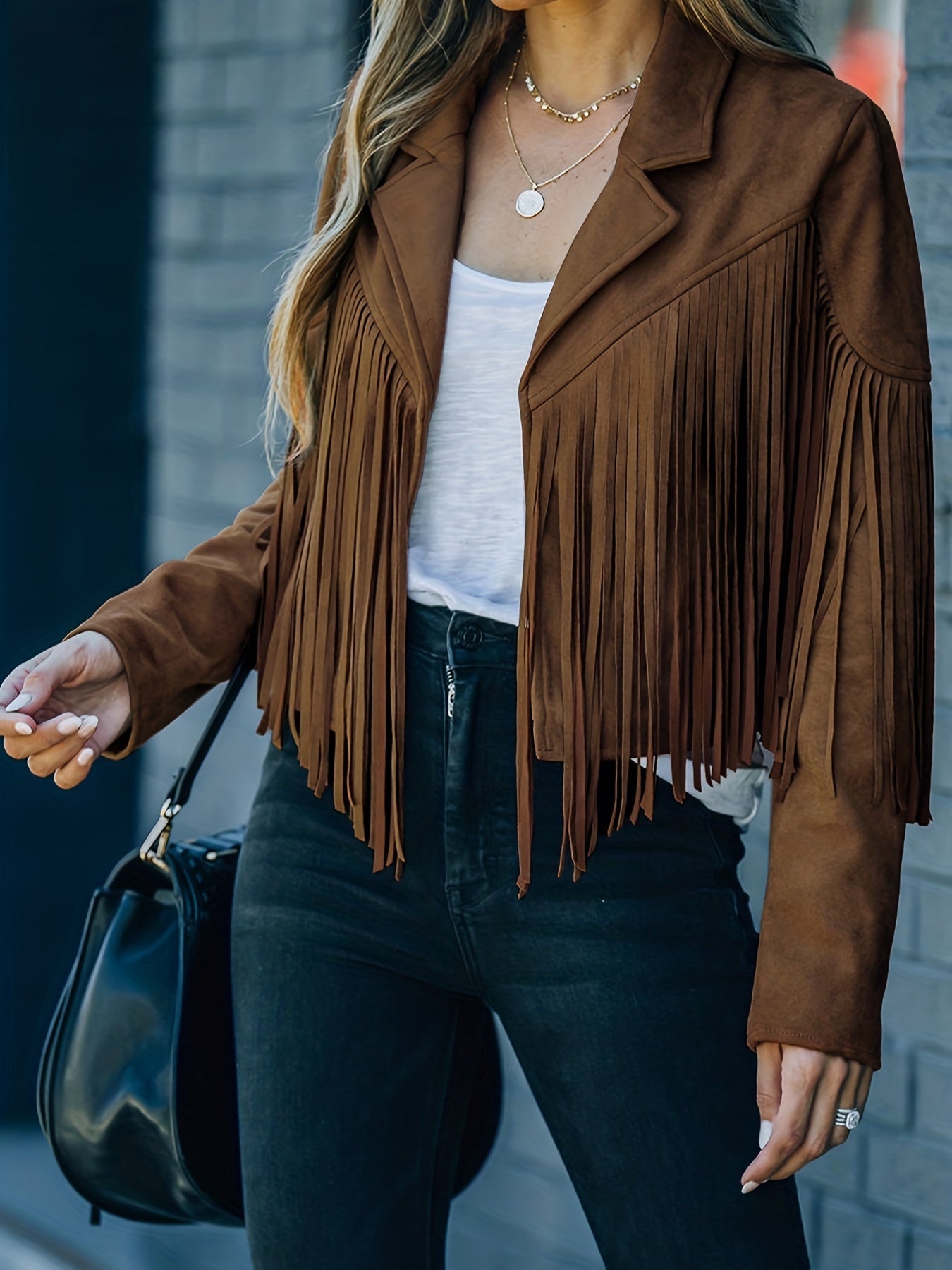 Braune Wildlederjacke mit Fransen, kombiniert mit weißem Top und schwarzer Hose. Perfekt für trendige Herbstmode und Western-Look.