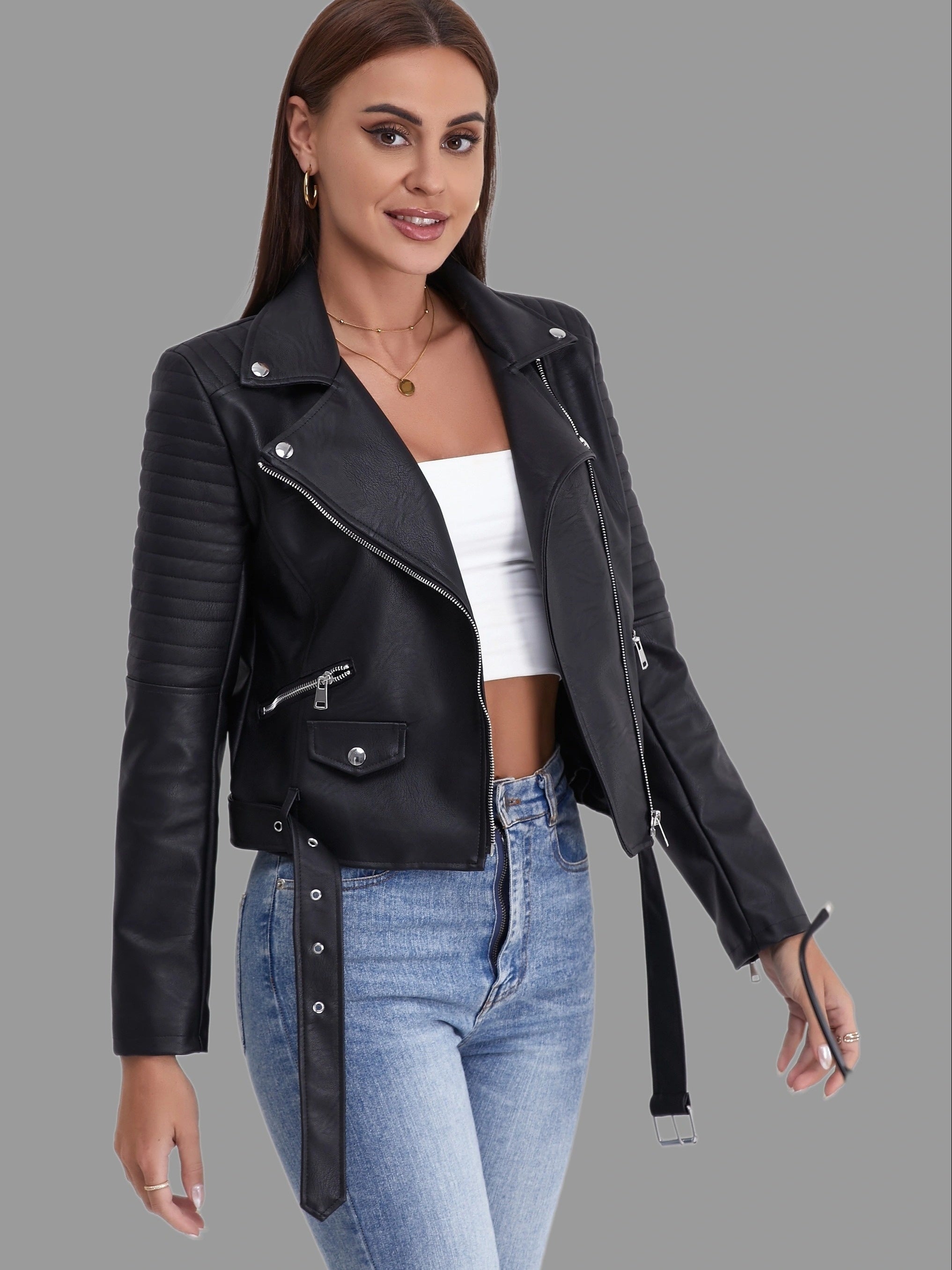 Damen-Lederjacke in Schwarz, Biker-Stil, mit Reißverschlüssen und Gürtel, kombiniert mit weißem Top und Jeans. Modisch, elegant, zeitlos.