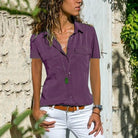 Frau in lila Bluse und weißer Hose vor Steinwand, Sommermode, Freizeitkleidung, Damenbekleidung.