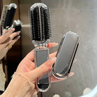 Faltbare Haarbürste mit Spiegel, schwarz-silber, tragbar, ideal für unterwegs, stilvolles Design.