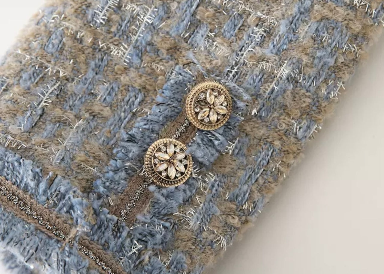 Elegantes Tweed-Stoffmuster in Blau und Beige mit dekorativen Knöpfen, ideal für Mode, Textildesign und luxuriöse Bekleidung.