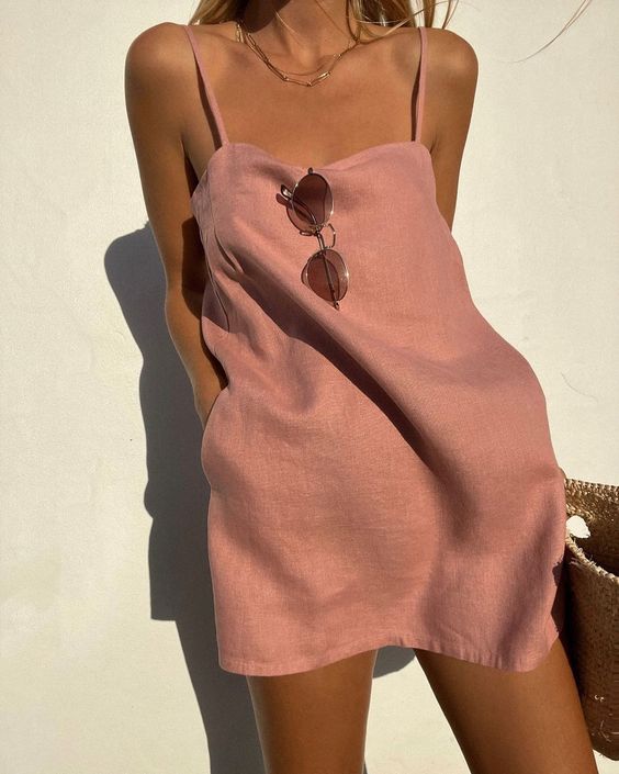 Damen-Sommerkleid in Rosa, ärmellos mit Spaghettiträgern, ideal für Strandmode. Perfekt kombiniert mit Sonnenbrille und Strohtasche.