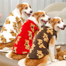 Drei Hunde in bunten, plüschigen Hundemänteln mit Teddybär-Muster sitzen nebeneinander. Perfekte Haustiermode für kalte Tage.
