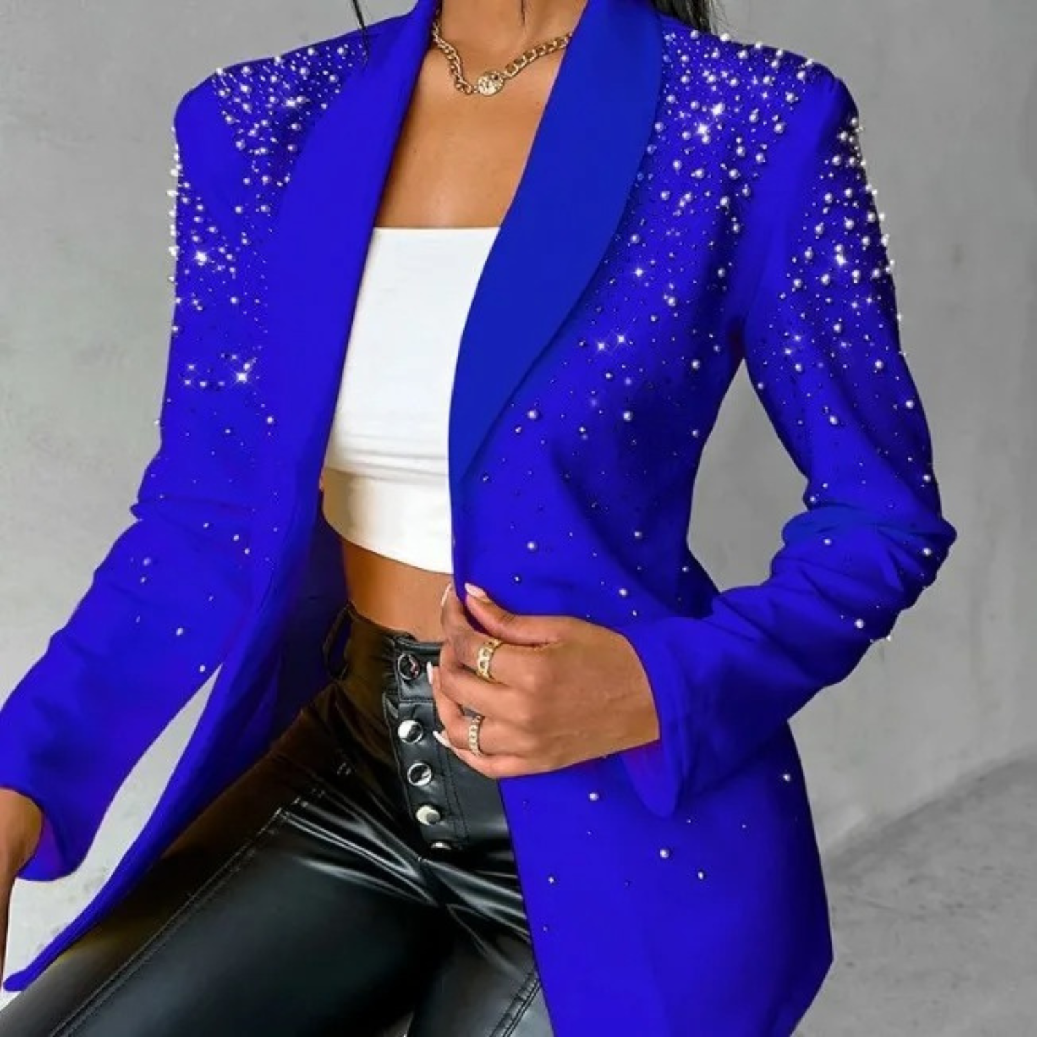 Eleganter blauer Blazer mit funkelnden Strasssteinen, kombiniert mit weißem Top und schwarzer Lederhose. Perfekt für modische Anlässe.