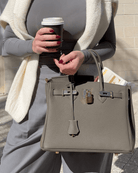 Frau mit grauer Lederhandtasche und Kaffeebecher, modisch, elegant, Accessoire, Herbstmode.