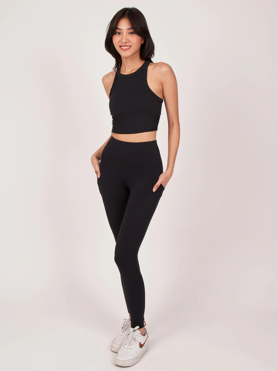 Frau in schwarzem Sport-BH und Leggings, ideal für Yoga und Fitness. Bequeme, atmungsaktive Sportbekleidung für aktive Frauen.