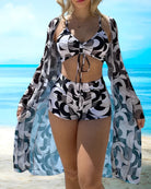 Frau in stilvollem Badeanzug mit geometrischem Muster am Strand, Sommermode, Strandkleidung, trendige Bademode, Urlaub, Meereshintergrund.