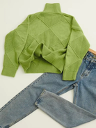Grüner Strickpullover mit Rautenmuster und blauer Jeans. Modischer Winterlook, gemütlicher Rollkragenpullover, lässige Damenmode, trendige Outfits.