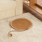 Kratzmatte aus Seil, rund, braun, für Katzen, auf Teppich neben Sofa, modernes Design.