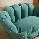 Grünes Katzenbett aus Stoff, muschelförmig, auf Teppich, gemütliches Haustiermöbel.
