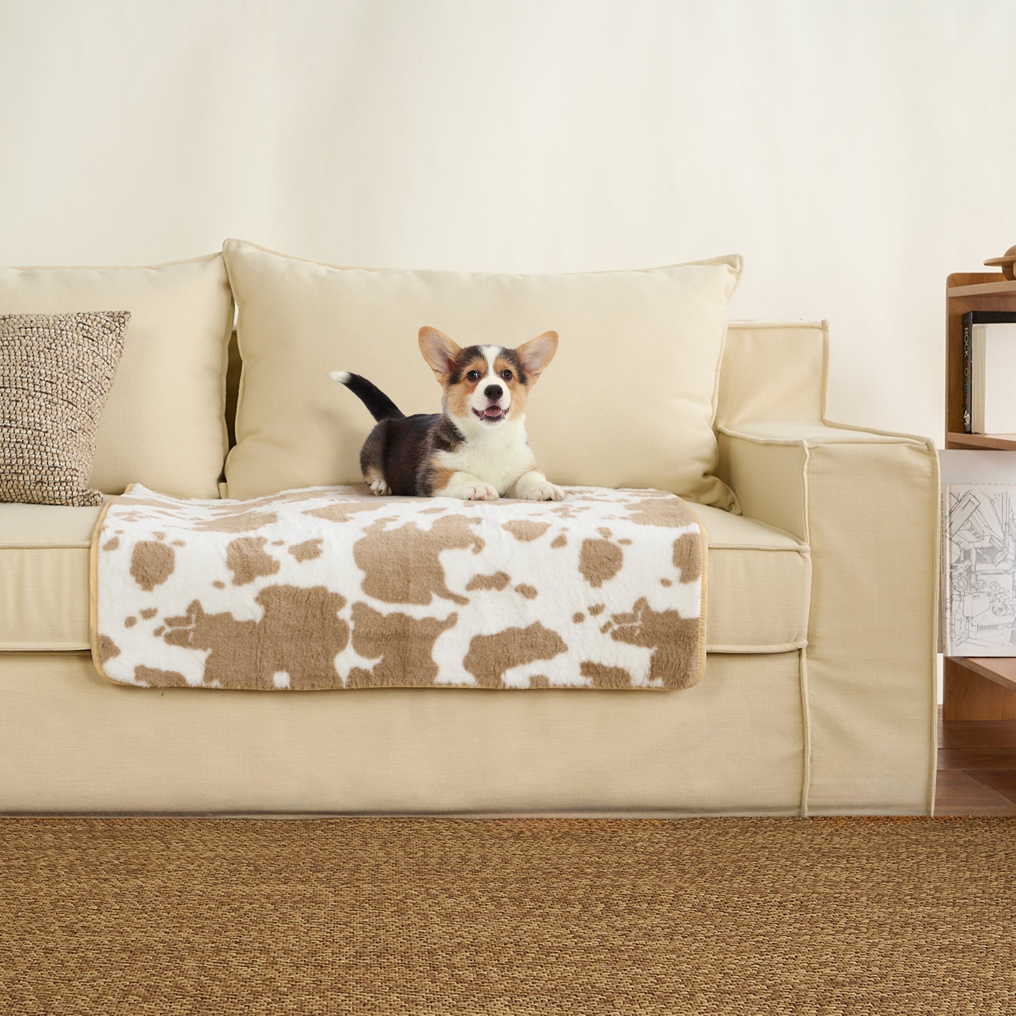 Hund auf beigem Sofa mit Kuhmuster-Haustiermatte, gemütlich, waschbar, Wohnzimmer-Dekor.
