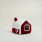 Rotes Katzenhaus aus Plüsch, schneebedeckt, mit Eingang, gemütliches Katzenbett, Winterdesign.
